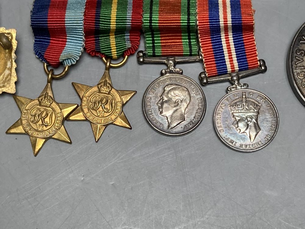 A WWII trio and a WWI pair, a collection of cap badges and non matching WWII miniatures
